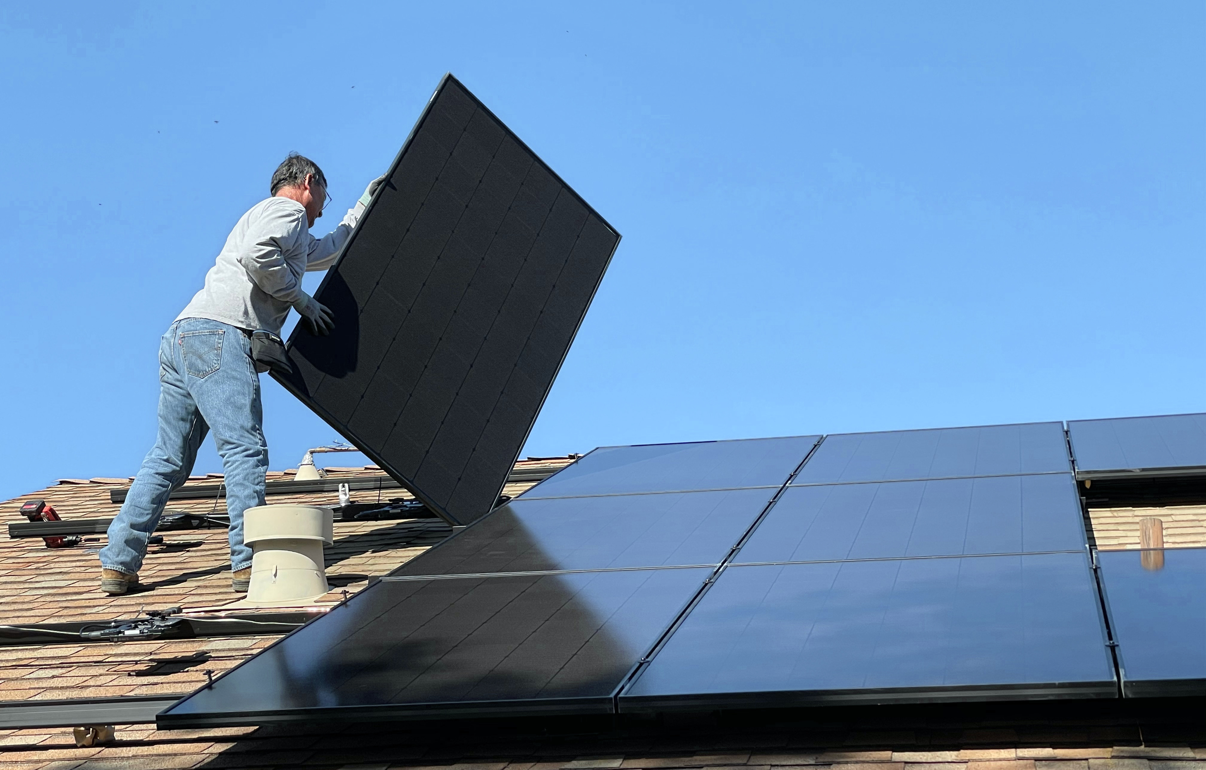 Ein Mann, der ein Solarpanel auf einem Dach anbringt